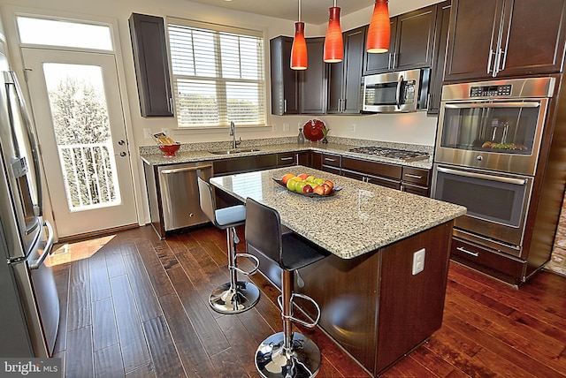 kitchen featuring a kitchen island, decorative light fixtures, sink, a breakfast bar area, and stainless steel appliances