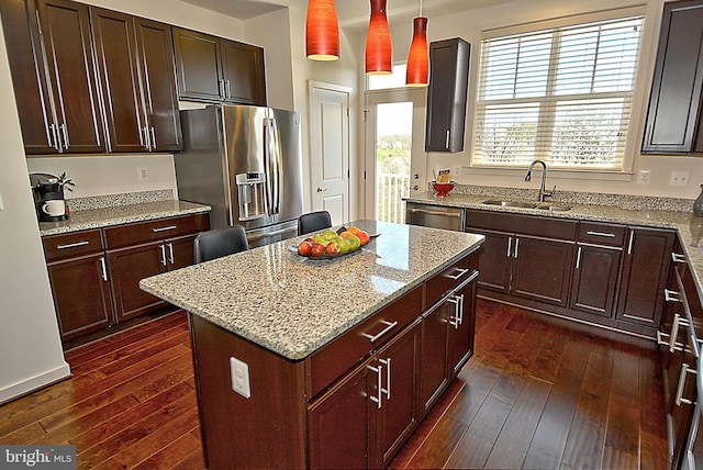 kitchen featuring sink, dark wood-type flooring, stainless steel appliances, a kitchen island, and decorative light fixtures