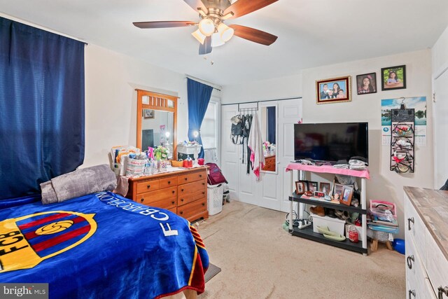 bedroom with light carpet, ceiling fan, and a closet