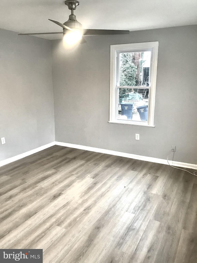 empty room featuring wood finished floors, a ceiling fan, and baseboards