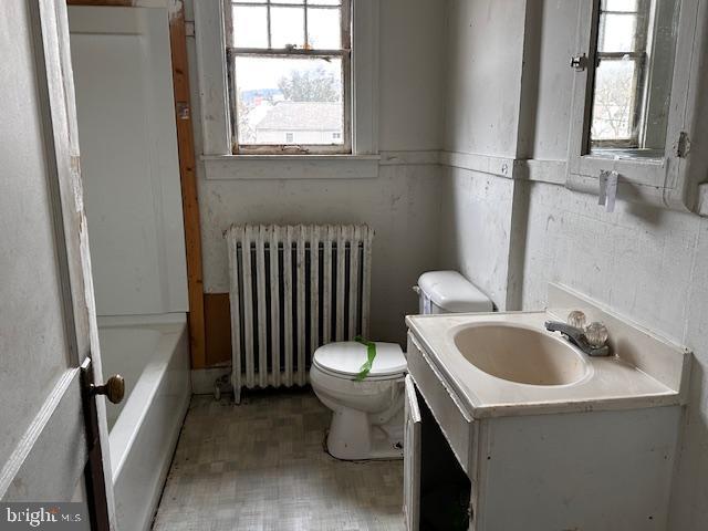 bathroom with vanity, radiator heating unit, toilet, and a bathing tub