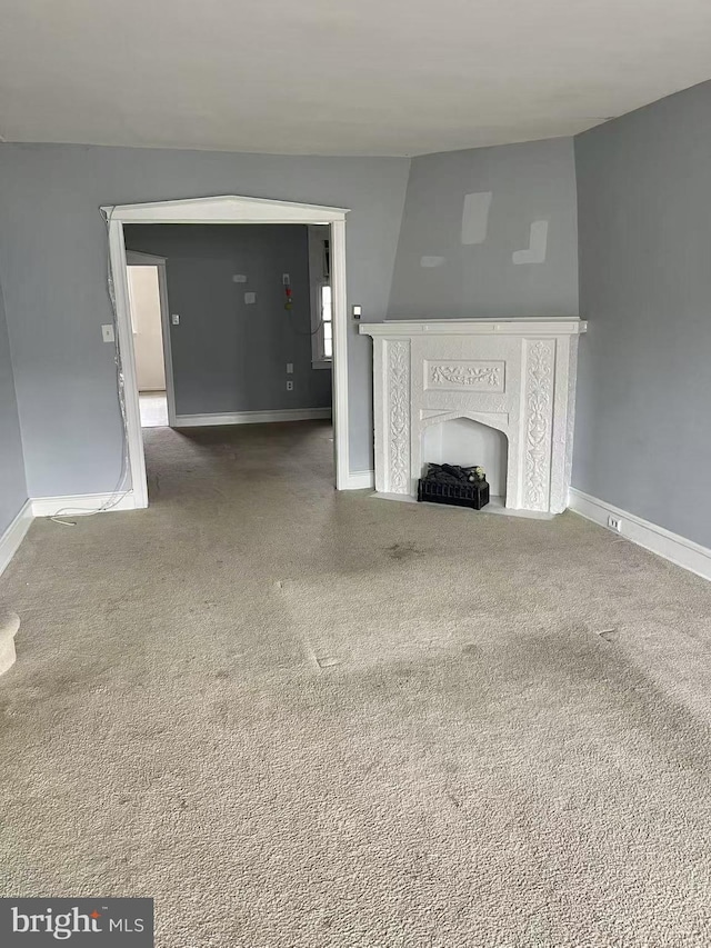 unfurnished living room with a premium fireplace and carpet flooring