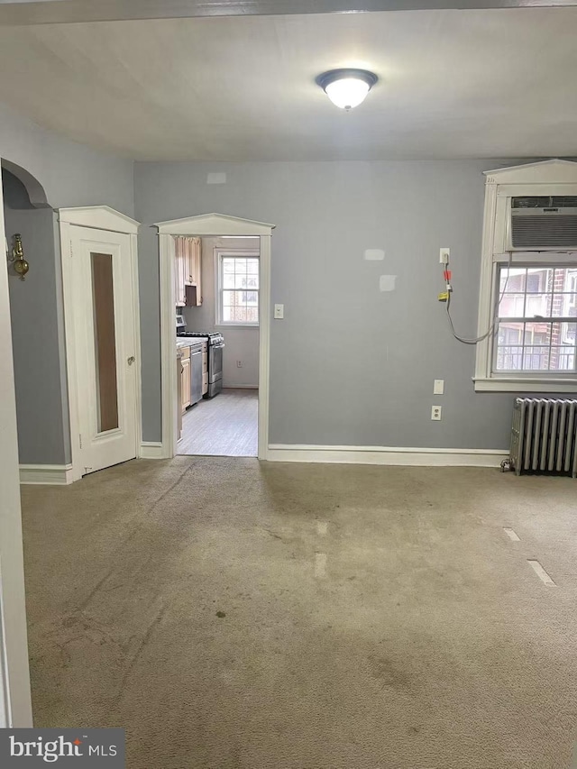 carpeted empty room with a wall mounted AC and radiator heating unit