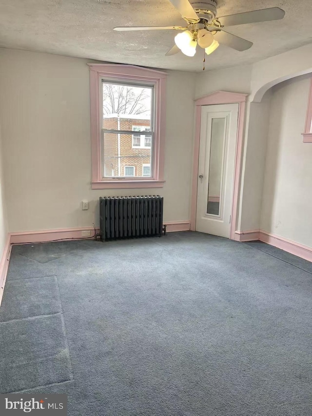 spare room with ceiling fan, carpet, radiator heating unit, and a textured ceiling