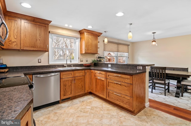 kitchen featuring sink, stainless steel dishwasher, kitchen peninsula, and decorative light fixtures