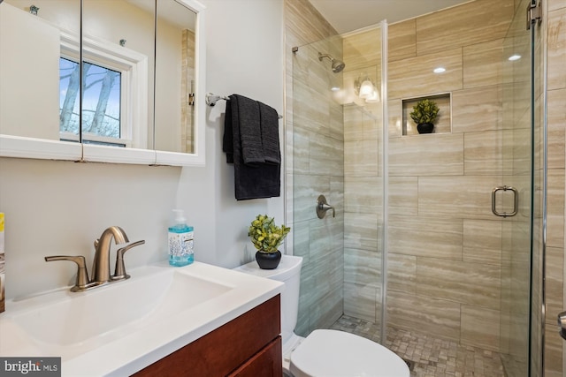 bathroom featuring vanity, a shower with shower door, and toilet