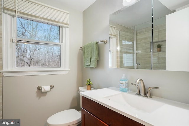 bathroom featuring vanity, a shower with door, and toilet