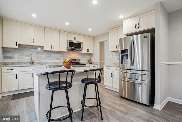 kitchen featuring light stone countertops, stainless steel appliances, and white cabinets