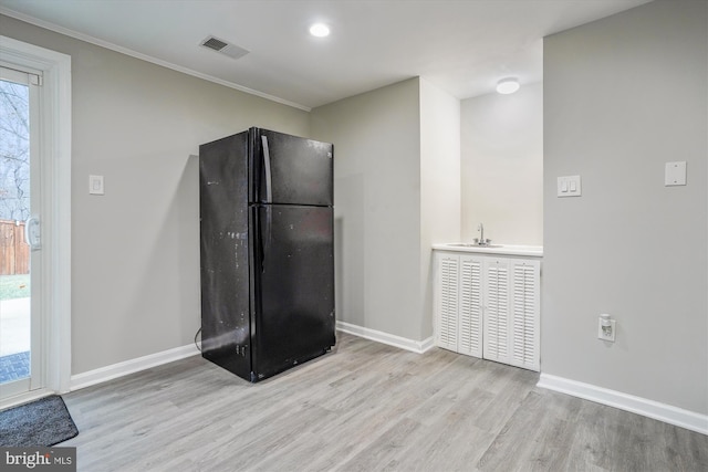 kitchen featuring ornamental molding, black refrigerator, sink, and light hardwood / wood-style flooring