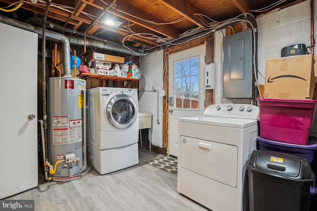 washroom featuring independent washer and dryer, electric panel, water heater, and light hardwood / wood-style flooring