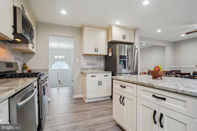 kitchen with light stone counters, tasteful backsplash, stainless steel appliances, and light hardwood / wood-style floors