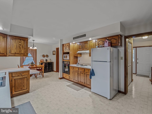 kitchen featuring white appliances, hanging light fixtures, and a notable chandelier