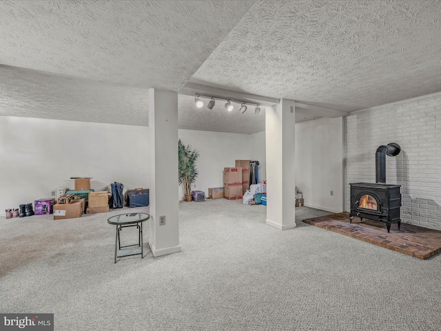 basement with a textured ceiling, carpet, and a wood stove