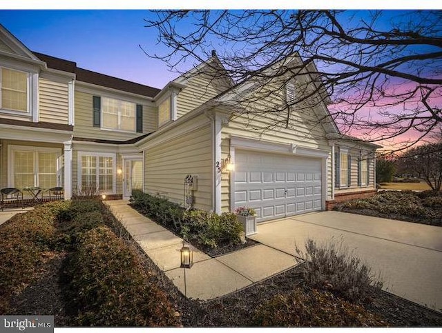 property exterior at dusk featuring an attached garage and concrete driveway