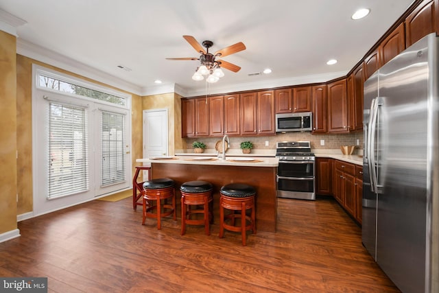 kitchen with appliances with stainless steel finishes, light countertops, crown molding, and dark wood-style floors