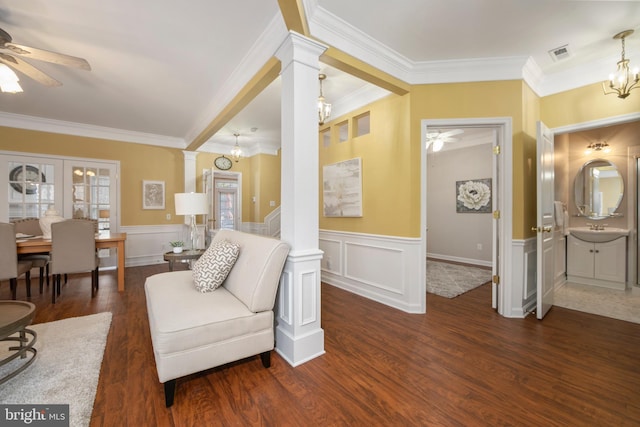 sitting room with ornate columns, visible vents, wood finished floors, and ceiling fan with notable chandelier