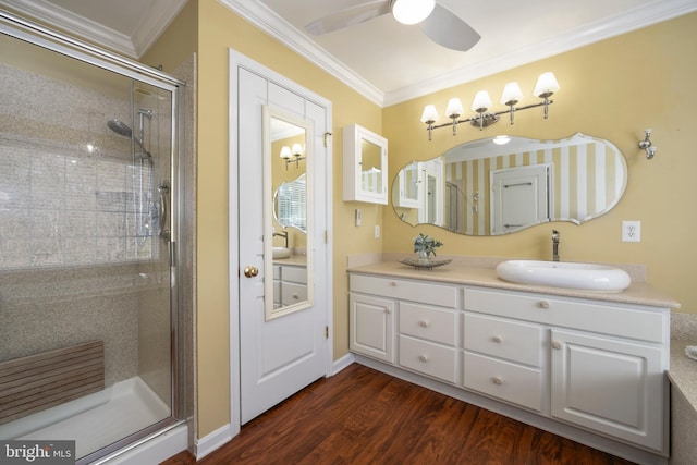 bathroom with a shower stall, vanity, crown molding, and wood finished floors