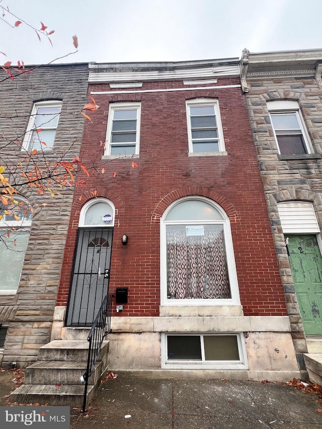 townhome / multi-family property featuring stone siding, brick siding, and entry steps