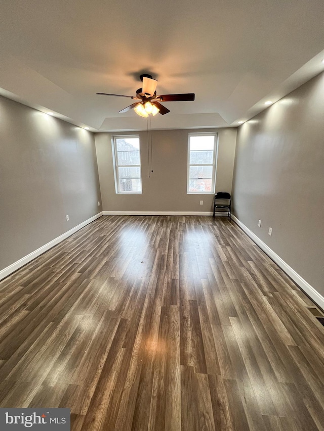 unfurnished room with dark wood finished floors, baseboards, and ceiling fan