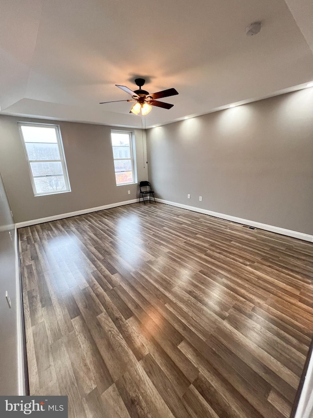 empty room with baseboards, dark wood-type flooring, and a ceiling fan