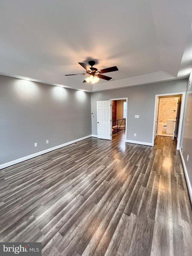 interior space with dark wood-style floors, a ceiling fan, and baseboards