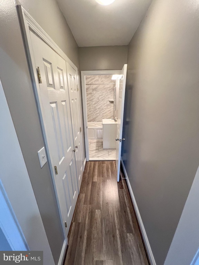 corridor featuring dark wood-style floors and baseboards