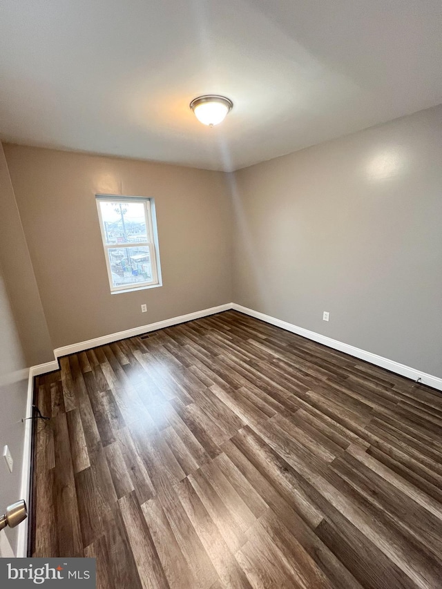 unfurnished room with baseboards and dark wood-style flooring