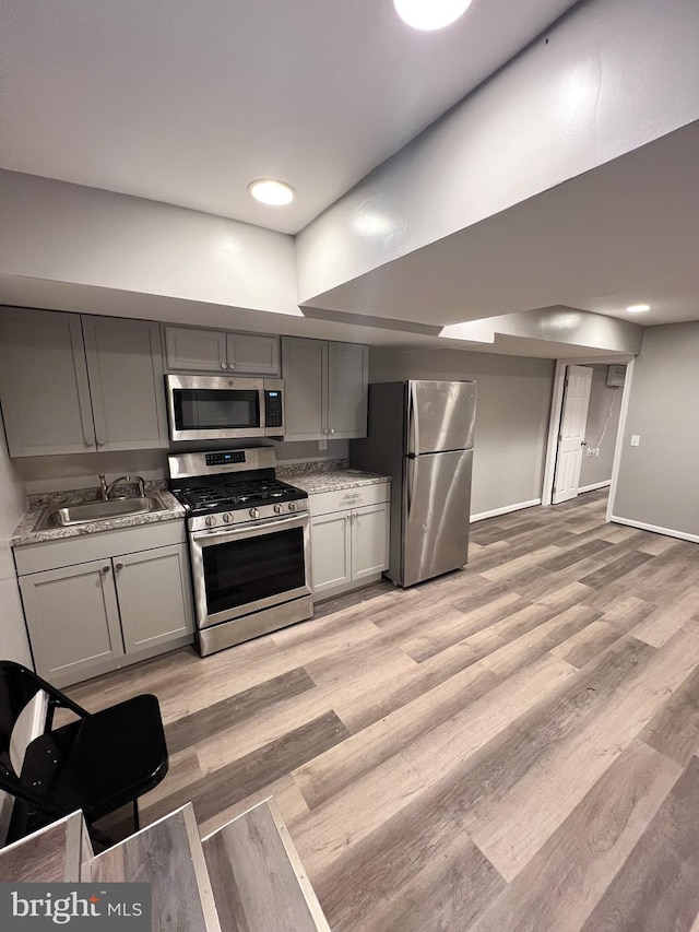 kitchen with light wood-style flooring, gray cabinets, appliances with stainless steel finishes, and a sink