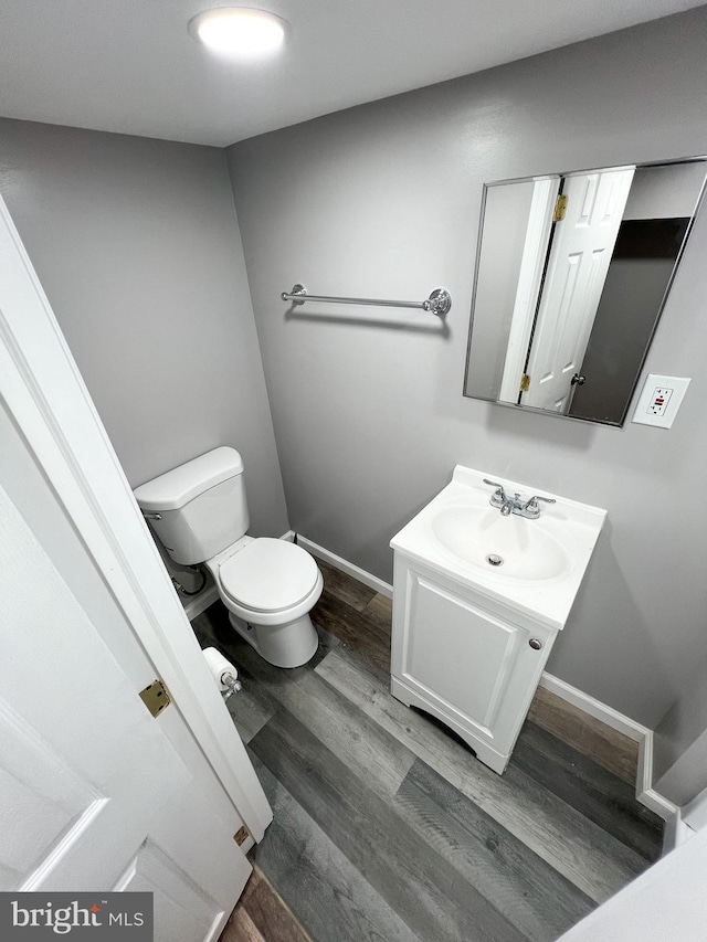 bathroom with baseboards, toilet, wood finished floors, and vanity