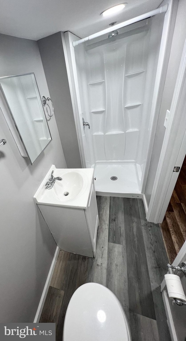 full bath with vanity, wood finished floors, a stall shower, and baseboards