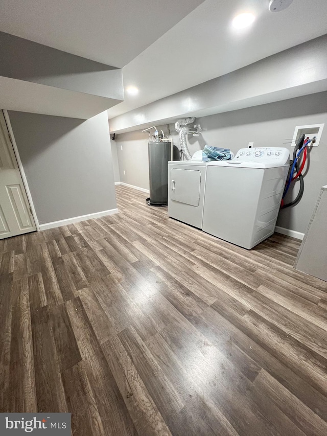 clothes washing area featuring wood finished floors, separate washer and dryer, water heater, and baseboards