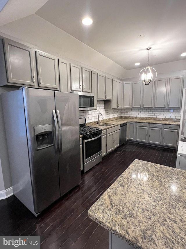 kitchen with decorative backsplash, appliances with stainless steel finishes, dark wood-type flooring, and a sink