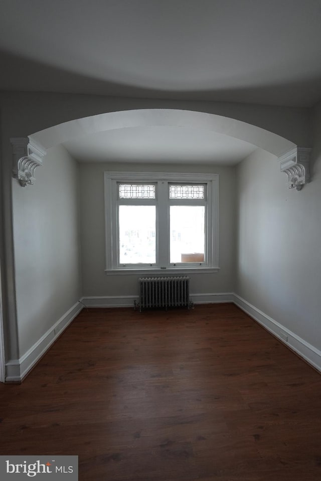 spare room featuring radiator heating unit and dark hardwood / wood-style floors