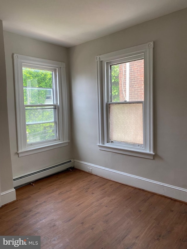 empty room with hardwood / wood-style flooring and a baseboard heating unit