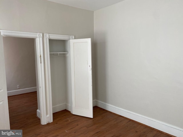 unfurnished bedroom with dark wood-type flooring and a closet