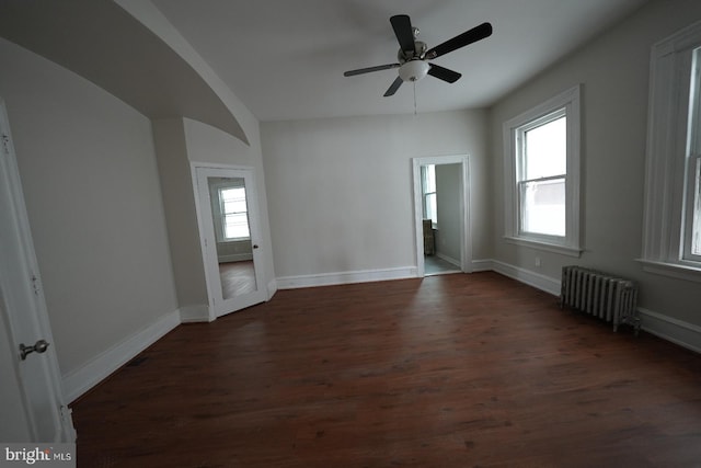 unfurnished room featuring dark hardwood / wood-style floors, radiator heating unit, and ceiling fan