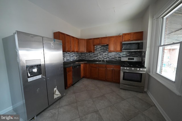 kitchen with stainless steel appliances, dark tile patterned floors, sink, and backsplash