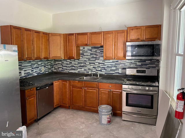 kitchen featuring stainless steel appliances, sink, backsplash, and dark stone counters