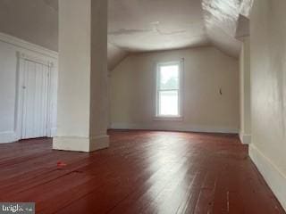 additional living space with vaulted ceiling and dark hardwood / wood-style floors