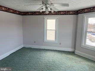 empty room with carpet floors, a textured ceiling, a wealth of natural light, and ceiling fan