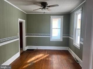 spare room featuring ornamental molding, a healthy amount of sunlight, ceiling fan, and dark hardwood / wood-style flooring