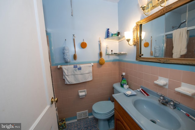 bathroom with walk in shower, vanity, toilet, and tile walls