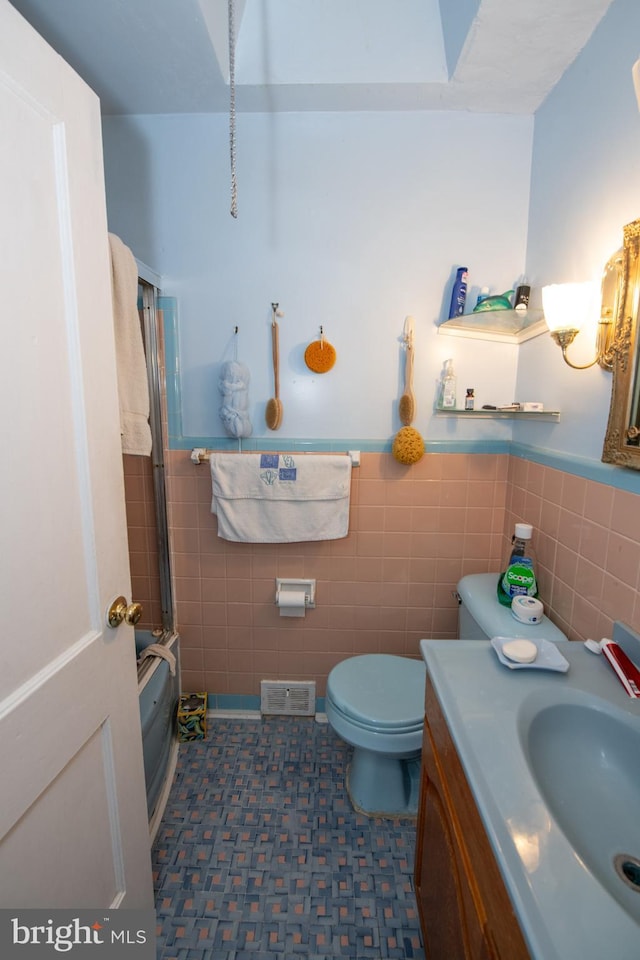 bathroom with vanity, tile walls, and toilet