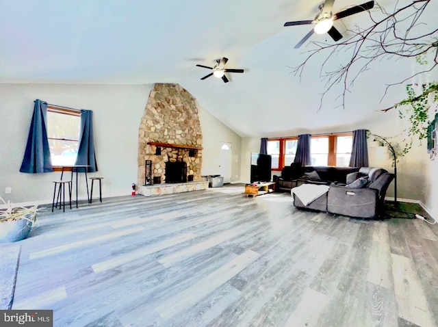 living room featuring hardwood / wood-style flooring, vaulted ceiling, ceiling fan, and a fireplace