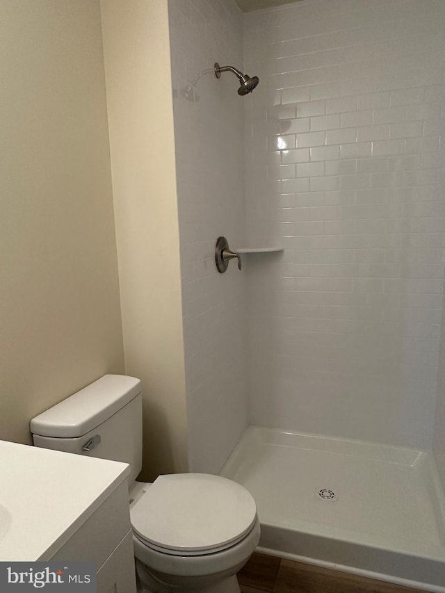 bathroom with tiled shower, vanity, and toilet