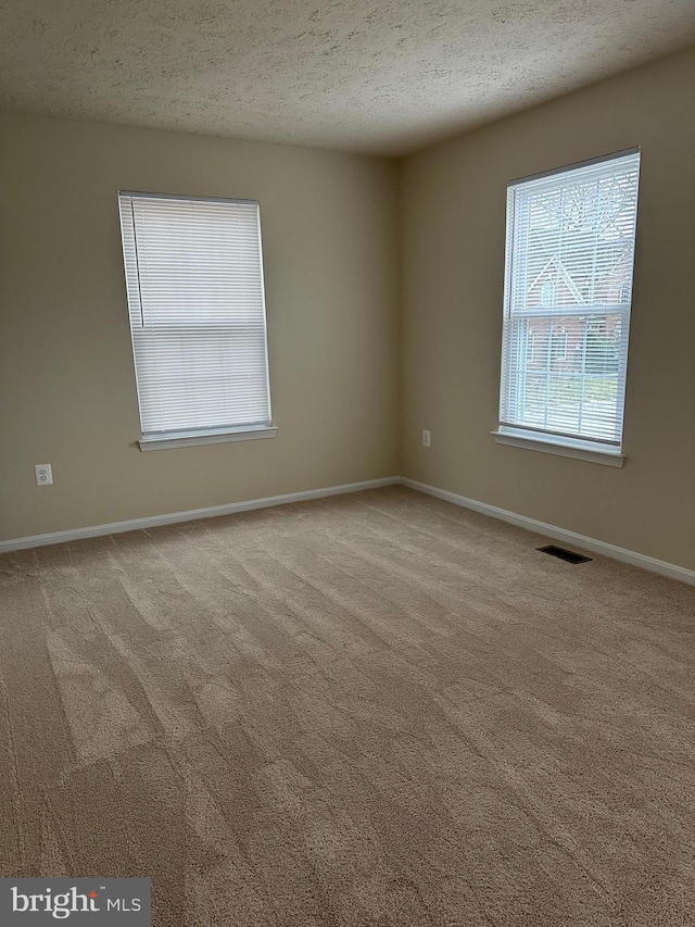 carpeted empty room featuring a textured ceiling