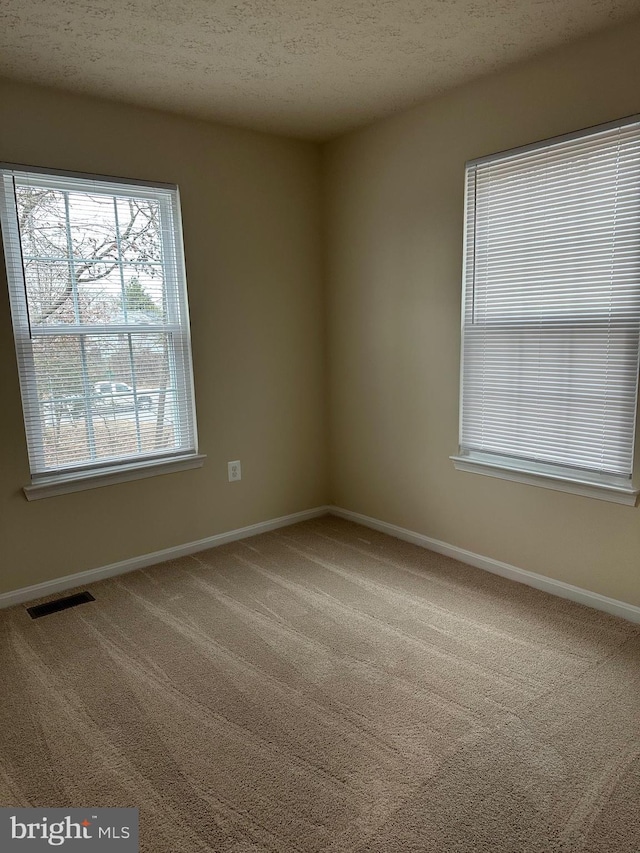 carpeted empty room with a textured ceiling