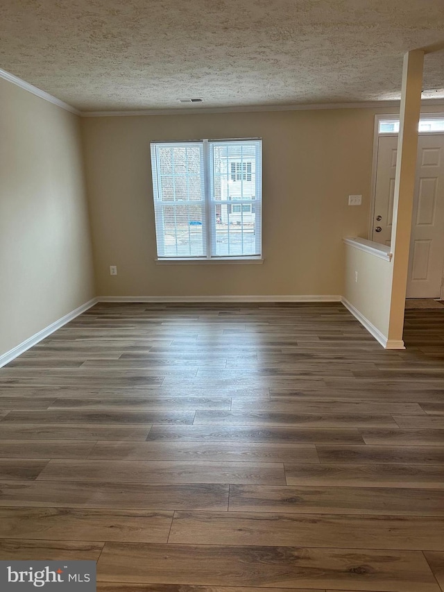 spare room featuring crown molding, dark hardwood / wood-style floors, and a textured ceiling