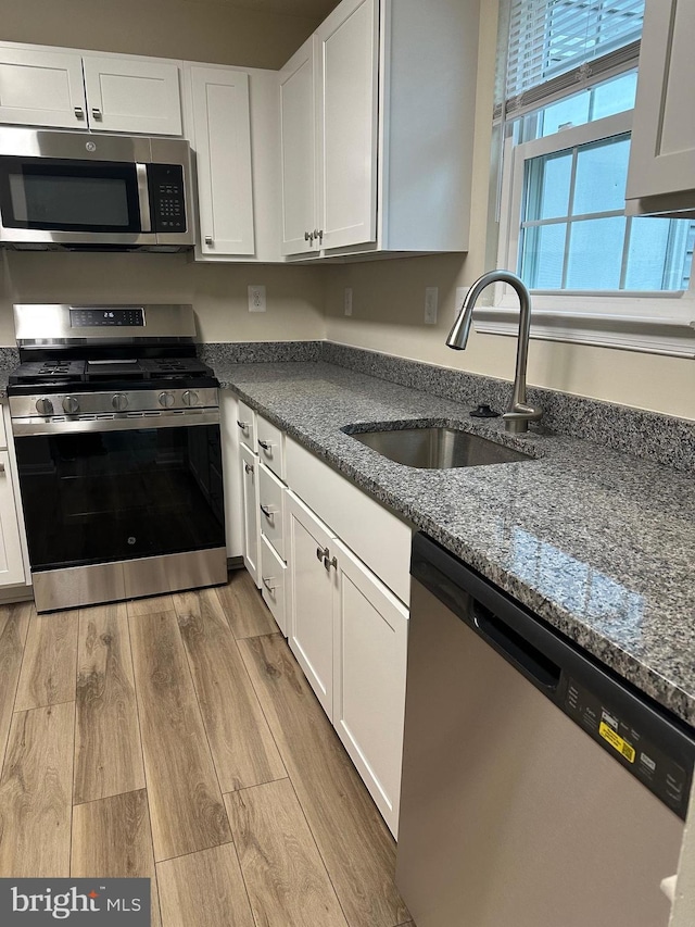 kitchen with white cabinetry, appliances with stainless steel finishes, sink, and light hardwood / wood-style flooring