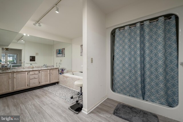 bathroom featuring vanity, a relaxing tiled tub, wood-type flooring, and track lighting